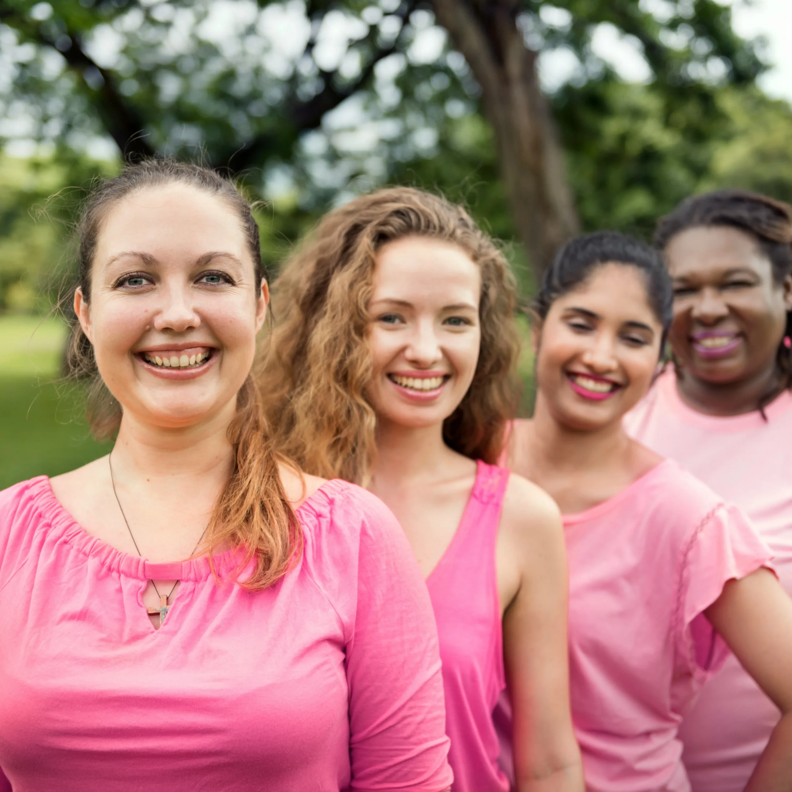 Empowered women all wearing pink shirts stand in a row supporting one another.